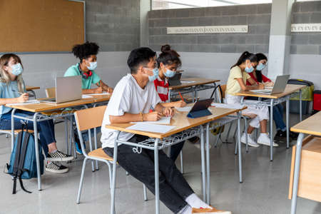 Group of multiracial teenager high school students in class wearing protective face masks. Education concept. Healthcare concept.の写真素材