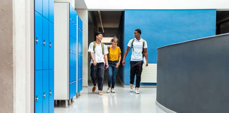 Group of teen high school students laughing walking in school corridor. Horizontal banner image. Copy space. Back to school. Education concept.の写真素材