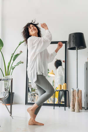 Young happy mixed race woman dancing at home with enjoyment. At home concept. Dancing concept.の写真素材