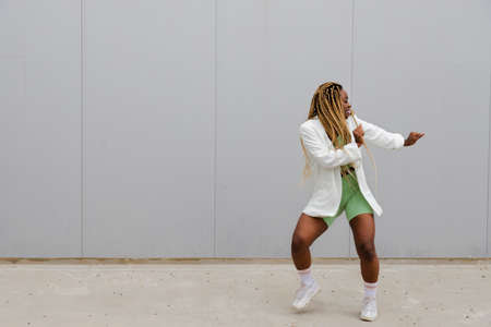 Young african american woman with long blond braids dancing in the street. Copy space. Urban dancing...