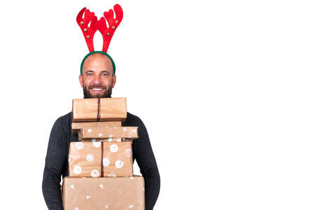 Portrait of young man with reindeer antlers looking at camera carries Christmas presents. White...