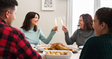 Mother and daughter toasting with champagne during Christmas dinner party. Family gathering. Horizontal banner.の写真素材