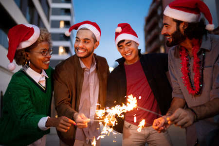 Multiracial friends celebrate Christmas together with sparklers wearing santa claus hats.の写真素材