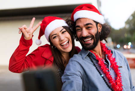 Smiling friends wearing santa hats take selfie. Christmas time.の写真素材
