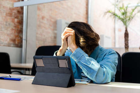 Young caucasian man frustrated and overwhelmed with work in the office. Copy space.