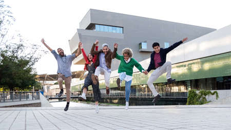 Multiracial group of friends jumping in the air in a city square. Copy space. Horizontal banner image.の写真素材