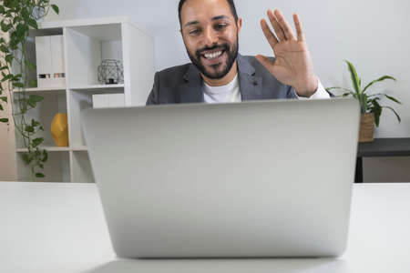 Happy smiling african american businessman on business video call waving his hand using his laptop.