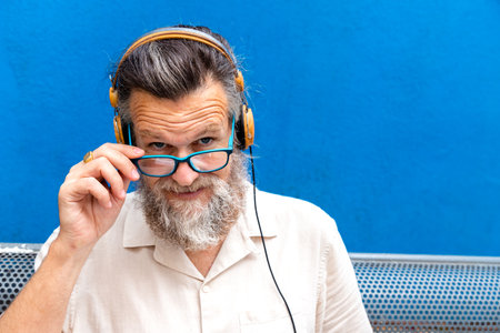 Portrait of mature caucasian man with headphones wearing eyeglasses looking at camera. Copy space.の写真素材
