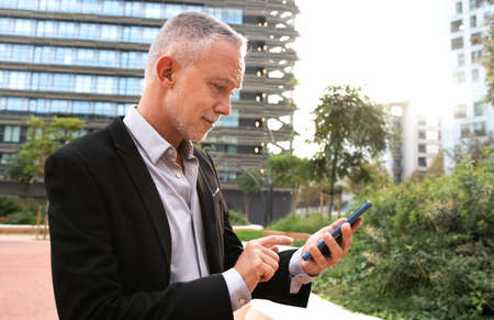 Caucasian business man using mobile phone to check e-mail and text messages. Copy space.