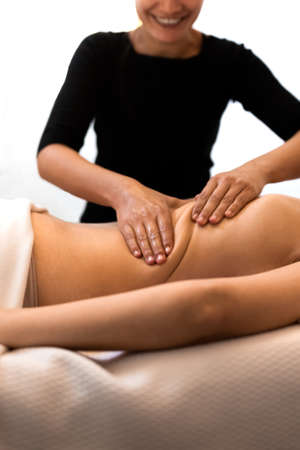 Happy masseuse working on female client mid back enjoying her job. Woman receiving massage relaxing in spa.の写真素材