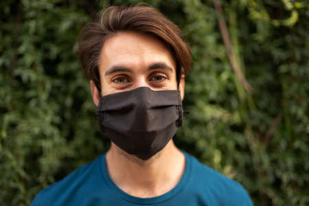 Portrait of young caucasian man wearing protective face mask looking at camera. Copy space.