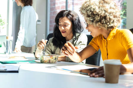 Lunch break at the office. Multiracial female coworkers have lunch at the workplace.の写真素材
