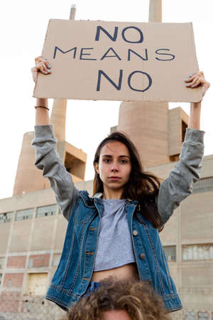 Portrait of young confident woman hold no means no banner in woman empowerment demonstration . Sitting on mans shoulder.の写真素材
