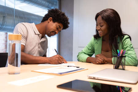 Two african american people signing contract in office.の写真素材