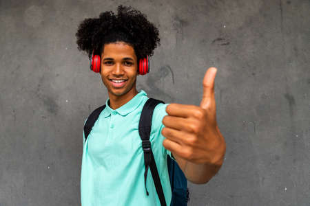 African American teenage boy with Afro hairstyle shows thumbs up looking at camera.の写真素材