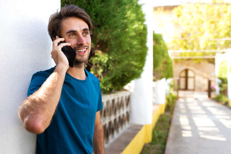 Young caucasian man talking on mobile phone in a park outdoors.Copy space.
