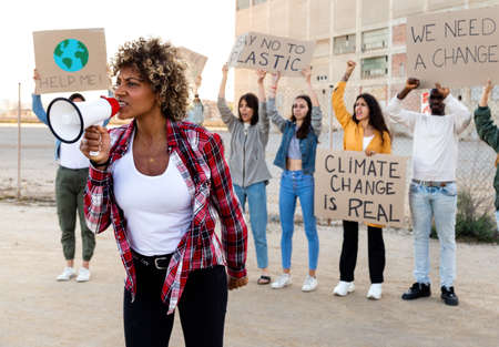 African American woman shouting through megaphone leading demonstration protesting against climate change.の写真素材