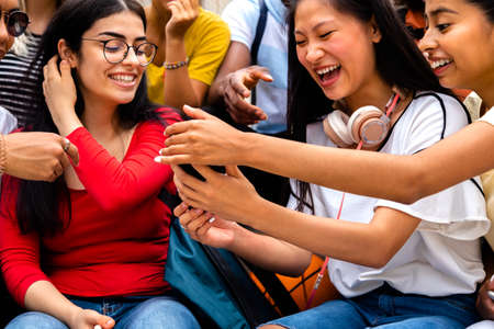 Close up of multiracial teen girls using mobile phone to look social media apps.の写真素材