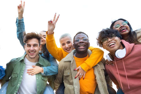 Multiracial teen college friends having fun outdoors.Boys piggy back ride girls.