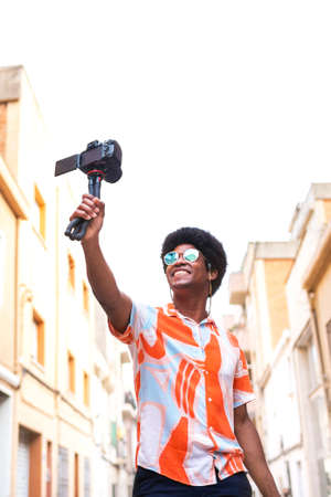 Young African American man vlogging his vacation trip for social media platform. Copy space. Vertical image.の写真素材