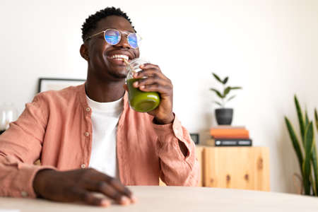 African American black man drinking healthy green juice with bamboo straw looking at camera. Copy space.の写真素材