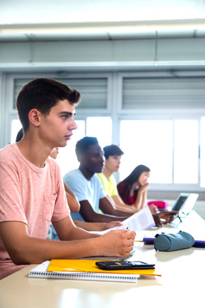 College male student in class listening to teacher. Multiracial high school students in classroom. Copy space. Vertical.の写真素材
