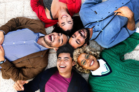 Happy multiracial friends lying down with heads touching forming a circle.の写真素材