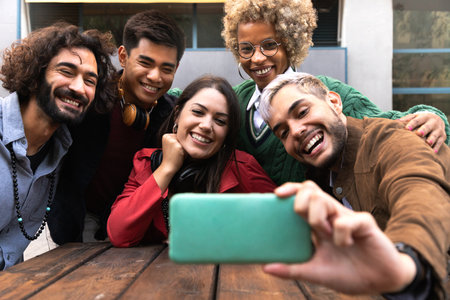 Smiling multiracial young friends take selfie together with mobile phone outdoorsの写真素材