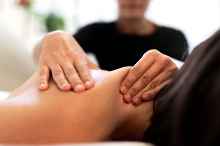 Close up of female hands giving back massage to woman. Selective focus.の写真素材