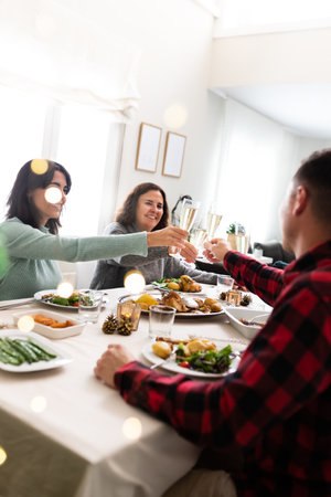 Cheers. Family Christmas gathering. Celebrate toasting with champagne. Raising the glasses. Vertical image. Copy space.の写真素材