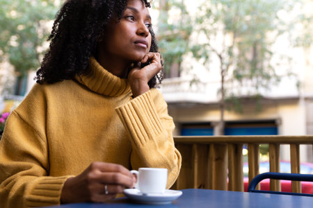 Pensive Young African American woman having espresso coffee in a cafe terrace in the city. Copy space.の写真素材