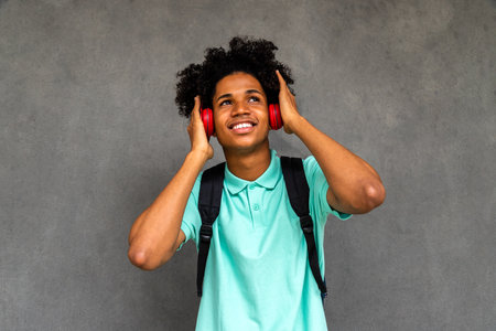 African American male teenager listens to music with headphones.