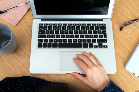 Top view of woman using laptop in office. Phone, notebook and eyeglasses. Working office.