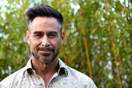 Portrait of adult white man with beard in nature looking at camera. Copy space.