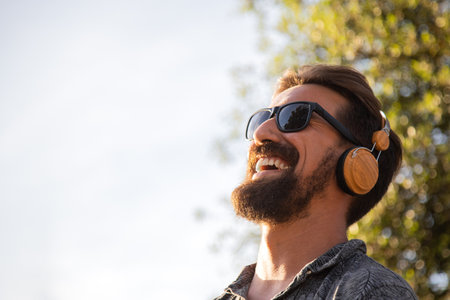 Smiling man relaxing listening to music with headphones surrounded by nature. Copy space.