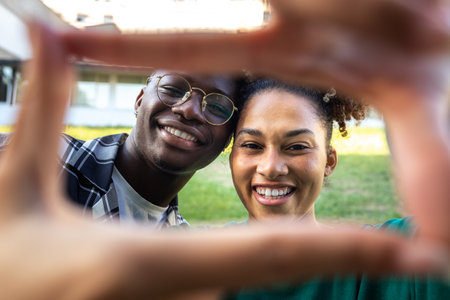 Happy, smiling young African American couple making frame with fingers looking at camera. Loving relationshipの写真素材