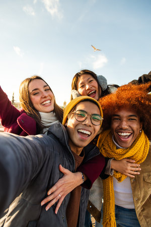 Selfie of multiracial happy friends enjoying winter day outdoors. Happy people looking at camera. Vertical. Copy space.の写真素材