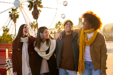 Group of happy multiracial college student friends laughing embracing together while walking around city on a winter dayの写真素材