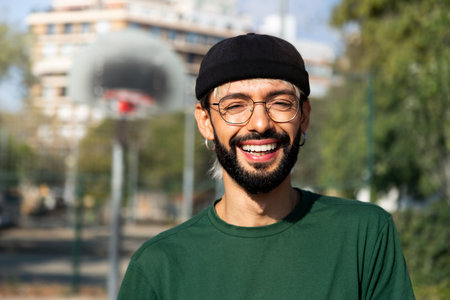 Headshot portrait of happy young caucasian man in basketball court outdoors looking at camera smiling. Copy space.の写真素材