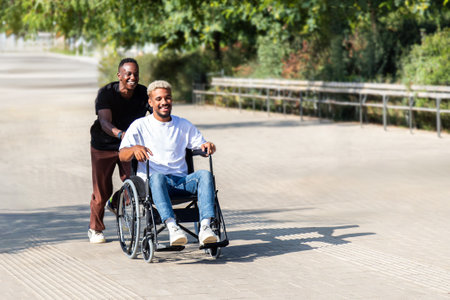 Black man running pushing his disabled African American male friend in a wheelchair in the city...