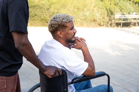 Side view of young disabled African American man in a wheelchair pensive looking away outdoors. Copy...