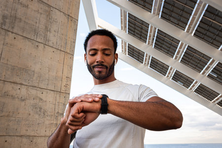 African American man checking pulse in smart watch. Black male with earphones using smart watch to put on music.の写真素材