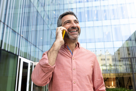 Mature happy caucasian man talking on the phone outdoors in the city.の写真素材