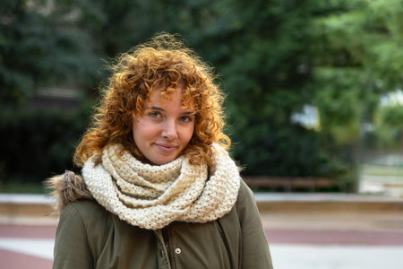 Young redhead happy woman looking at camera. Female in winter clothing outdoors. Copy space.