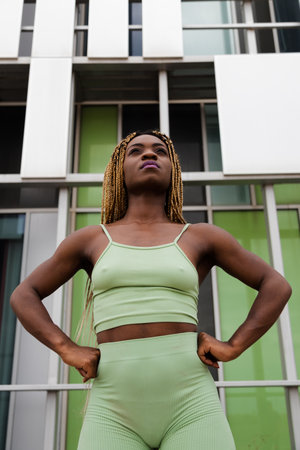 Low angle view vertical portrait of Confident, strong Black woman with braided hair looking up.の写真素材