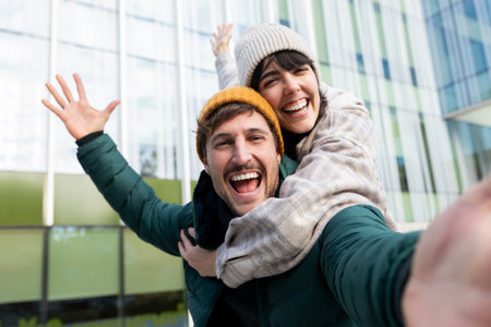 Happy couple taking selfie while having fun outdoors in winter looking at camera