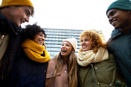 Low angle view of happy woman enjoying winter day with friends. Multiracial people embracing having fun laughing outdoorの写真素材
