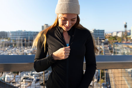Sportswoman zipping up her jacket before training in a marinaの写真素材