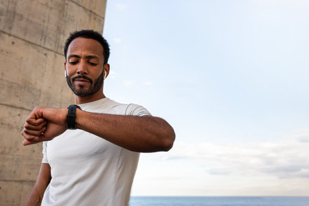 Athlete checks his smartwatch during a workout by the sea