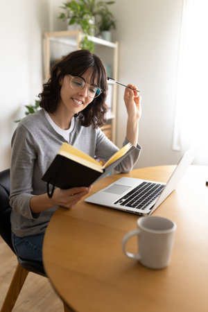 Woman working using laptop and notebook to organize and schedule business meetings.の写真素材